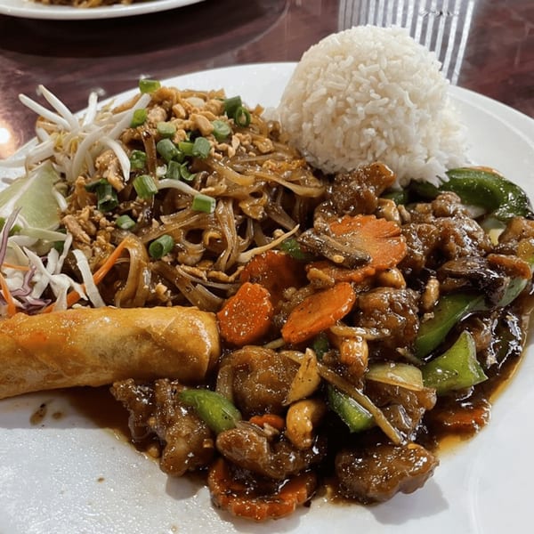 A Thai House plate with Pad Thai, white rice, an egg roll, and stir-fried meat and vegetables.