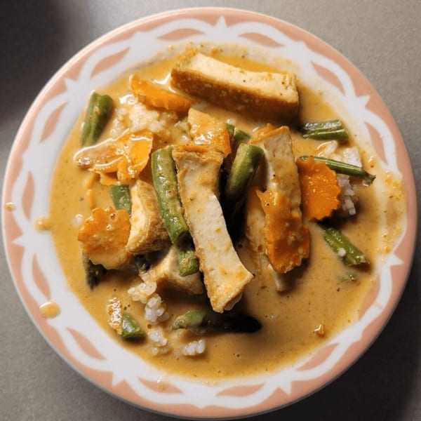 Our Thai House red curry with tofu, carrots, green beans, and rice in a bowl.