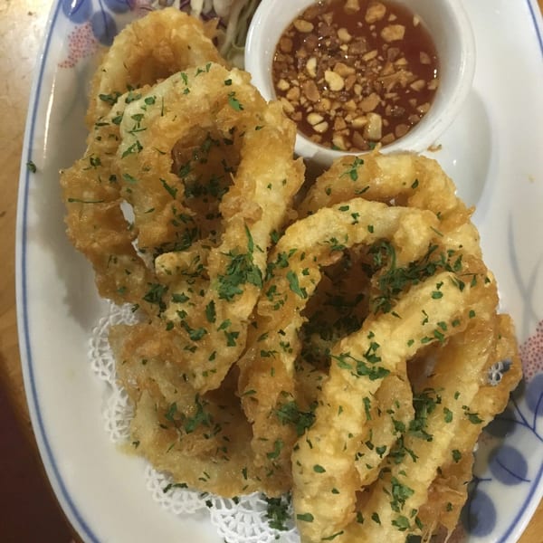 Crispy fried calamari rings, garnished with parsley, served with a sweet chili dipping sauce.