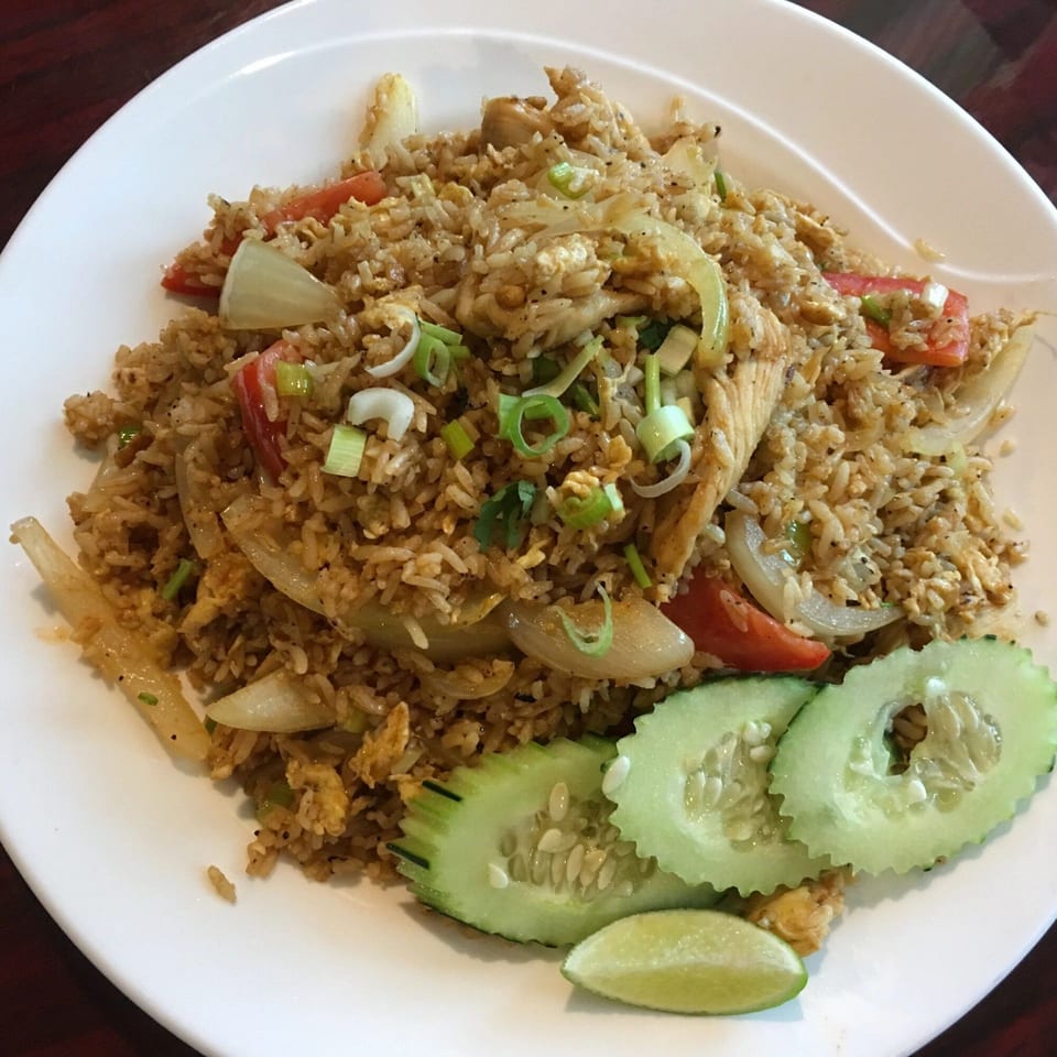 Our Thai House's chicken fried rice with vegetables, garnished with cucumber slices and a lime wedge.