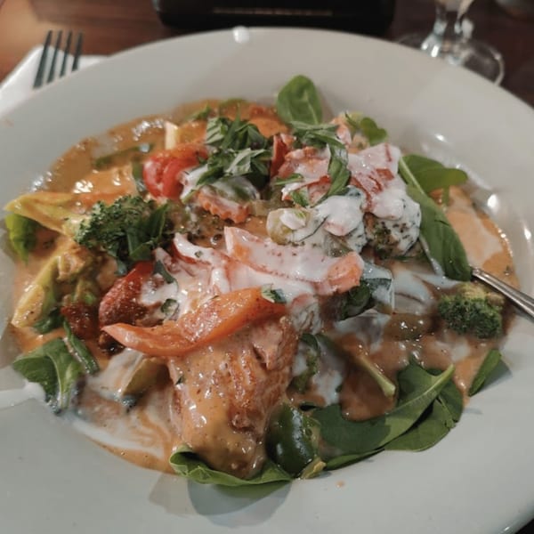 Our Thai House's red curry with vegetables, topped with fresh basil and a creamy drizzle.